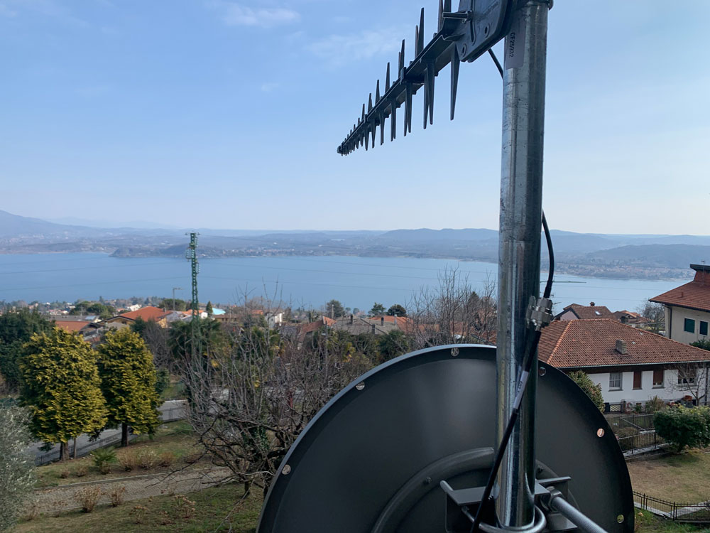 Locata dish antenna pointed to the European Union’s Joint Research Center in Ispra, Italy, 44 km away, just under the setting sun. The Yagi antenna above is pointed to a cell tower in Como and used to connect the system for remote control and data logging. (Image: Locata)
