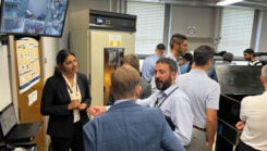 4. The top screen showing the hydrogen maser and cesium clocks in an adjacent isolated room used for realization of the timescale for research purposes. Students presenting their work to the USNO and Microchip Inc., visitors. (Photo: University of Alabama, Tuscaloosa)