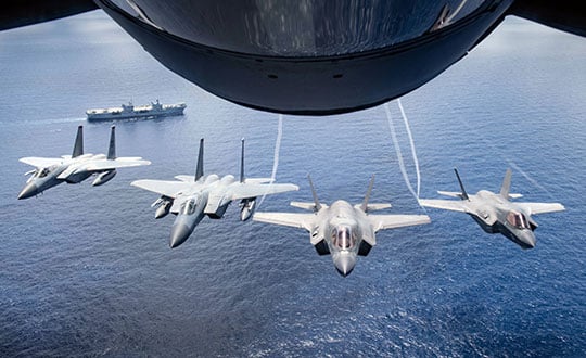 Two U.S. Marine Attack Squadron 211 F-35B Lightning IIs and two U.S. Air Force F-15 Eagles assigned to the 67th Fighter Squadron, fly over United Kingdom aircraft carrier HMS Queen Elizabeth over the west Indo-Pacific region in August 2021. (Photo: USAF/Staff Sgt. Kyle Johnson)