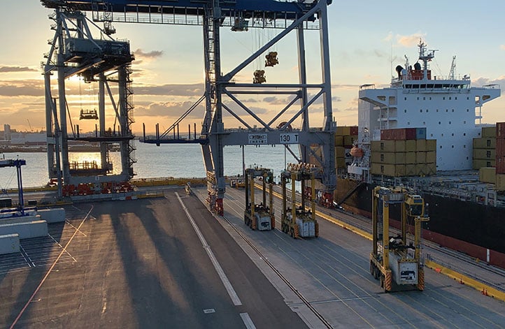 Locata-enabled manned straddles near STS cranes unload a ship at dusk. (Photo: Photo: David Small/Locata)